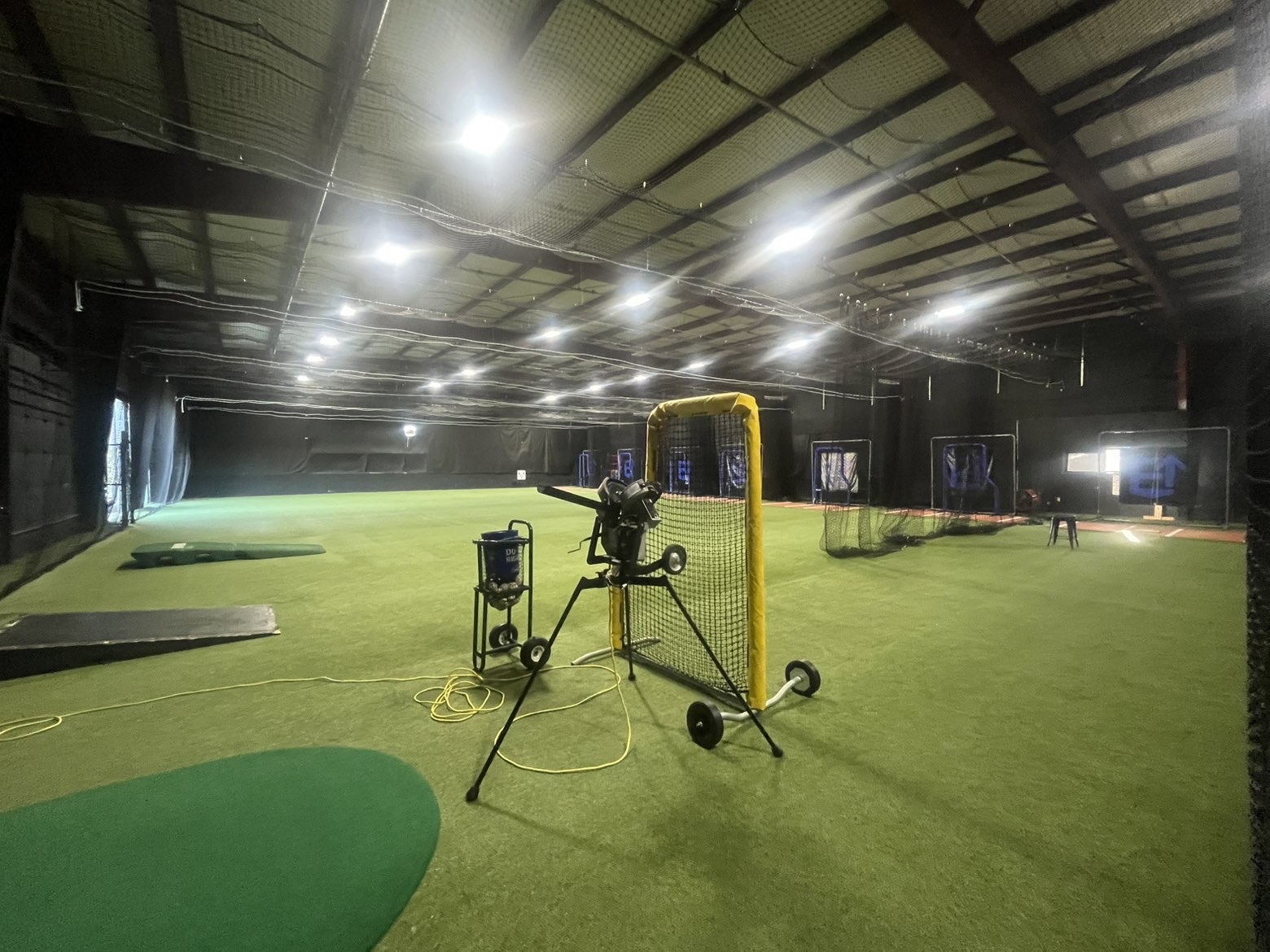 Indoor turf training area with pitching machine and netted cages