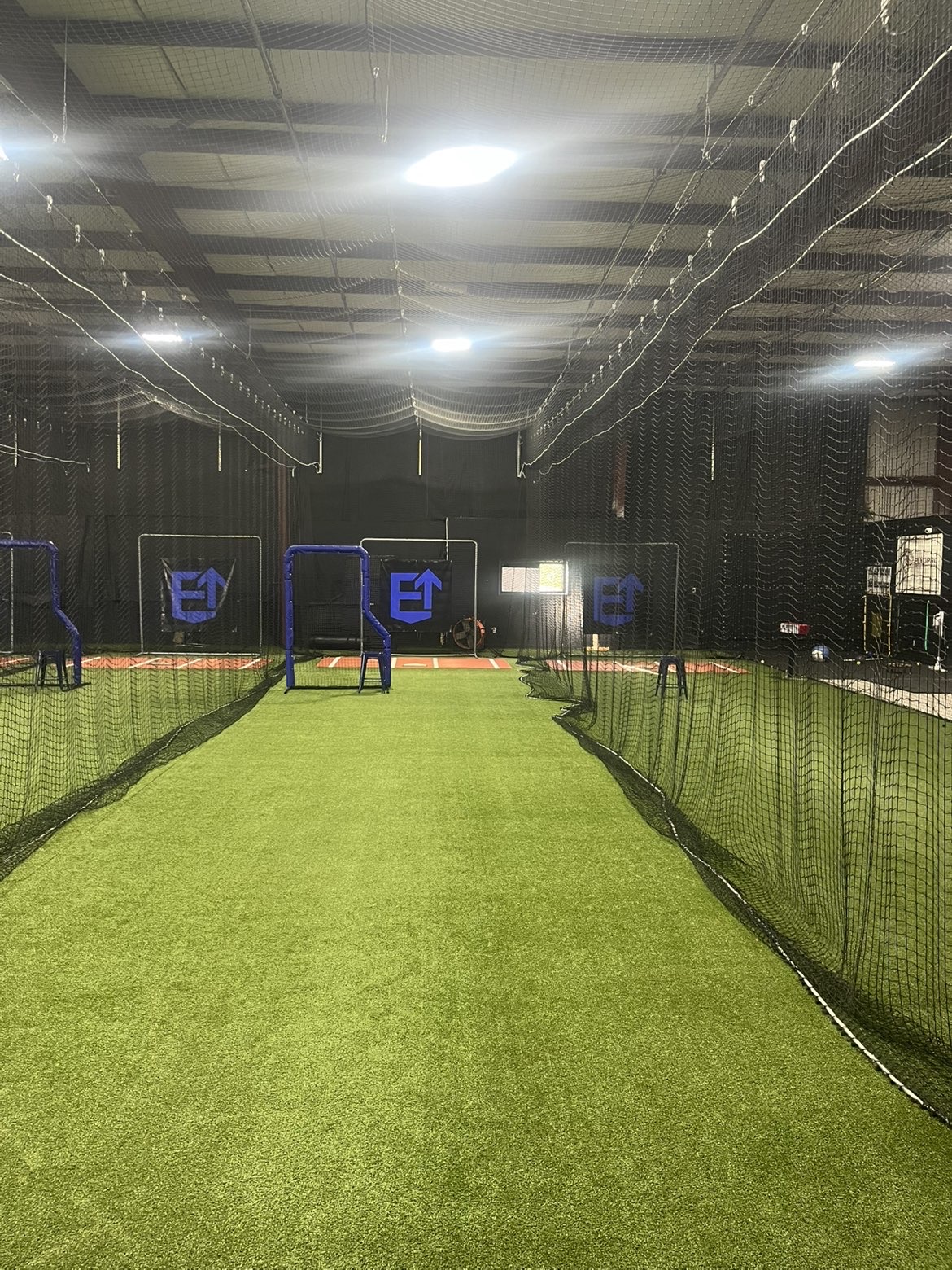 Netted batting lane with blue screens and Elevate branding